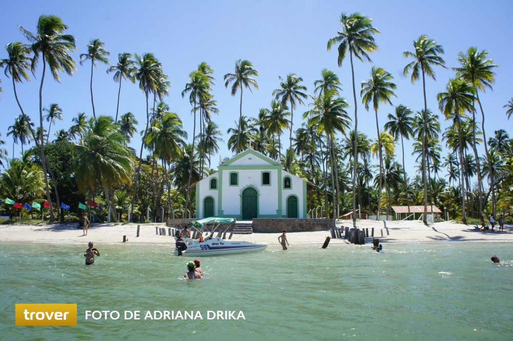 mar com capela de São Benedito ao fundo em meio aos coqueiros