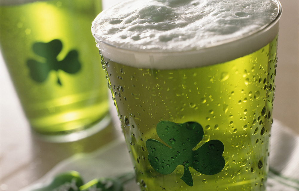 Dois copos de cerveja verde com um trevo de três folhas desenhado no copo