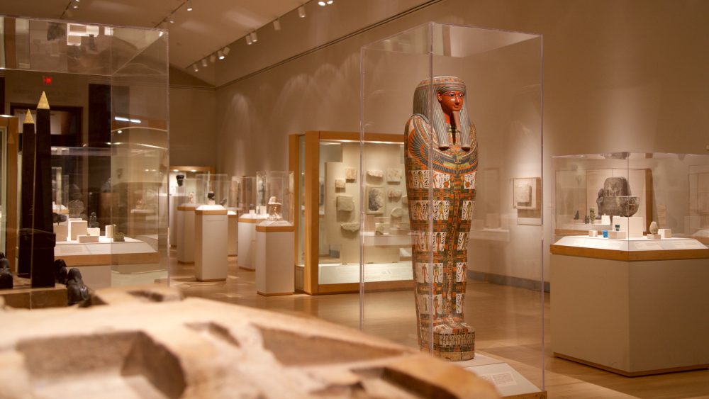 Sala do Museu do Brooklyn com a estátua de um faraó e outros objetos do Egito