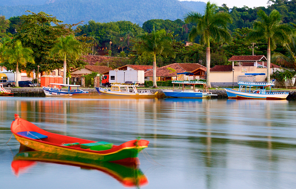 Barco na água em Paraty com casas ao fundo