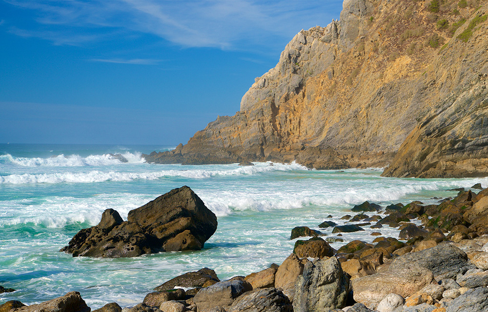 Pedras com ondas e uma grande pedra ao fundo