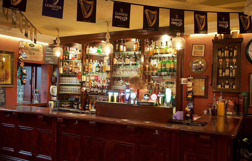 Balcão de um pub em Dublin com garrafas, copos e acessórios