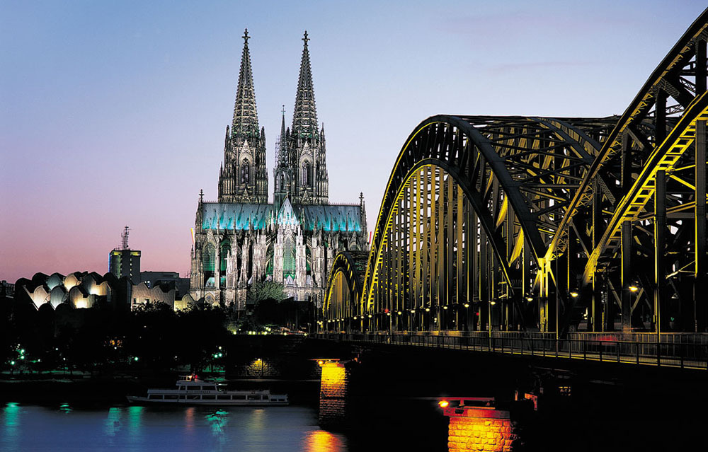 Catedral de Colônia ao fundo ao entardecer com uma ponte no primeiro plano