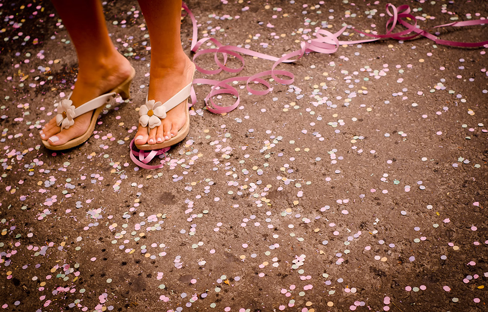 Mulher de sandálias dançando em um chão cheio de confetes e serpentina